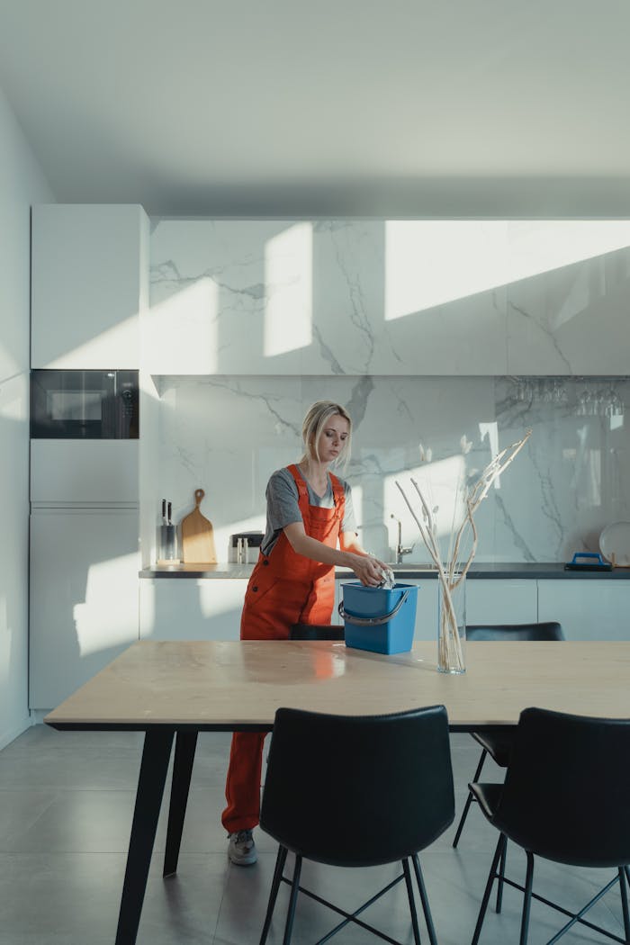 Crafting Captivating Headlines: Your awesome post title goes here A woman in uniform cleaning a modern kitchen lit by natural light, creating a serene atmosphere.